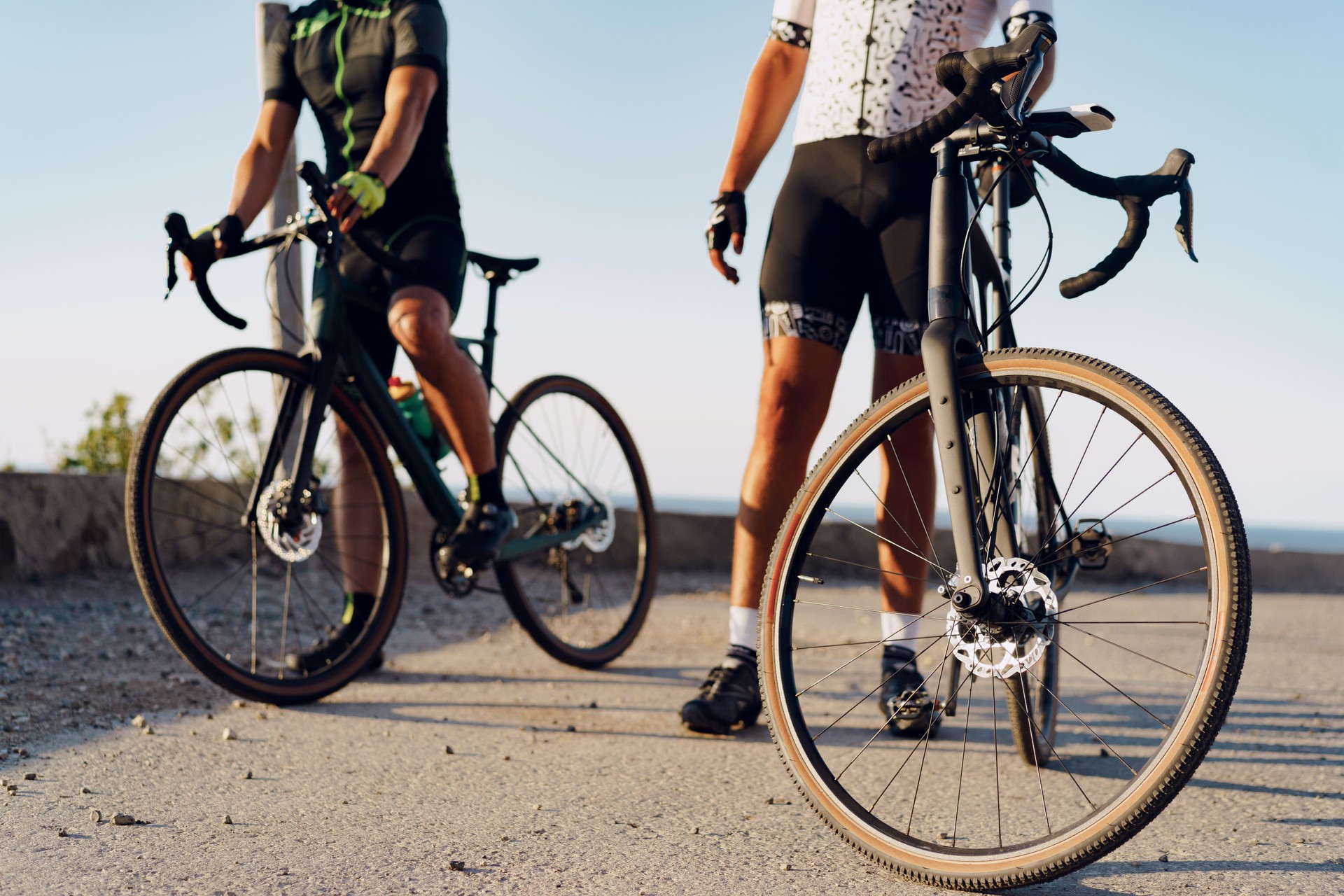 Two male cyclists stand on the road and have a rest
