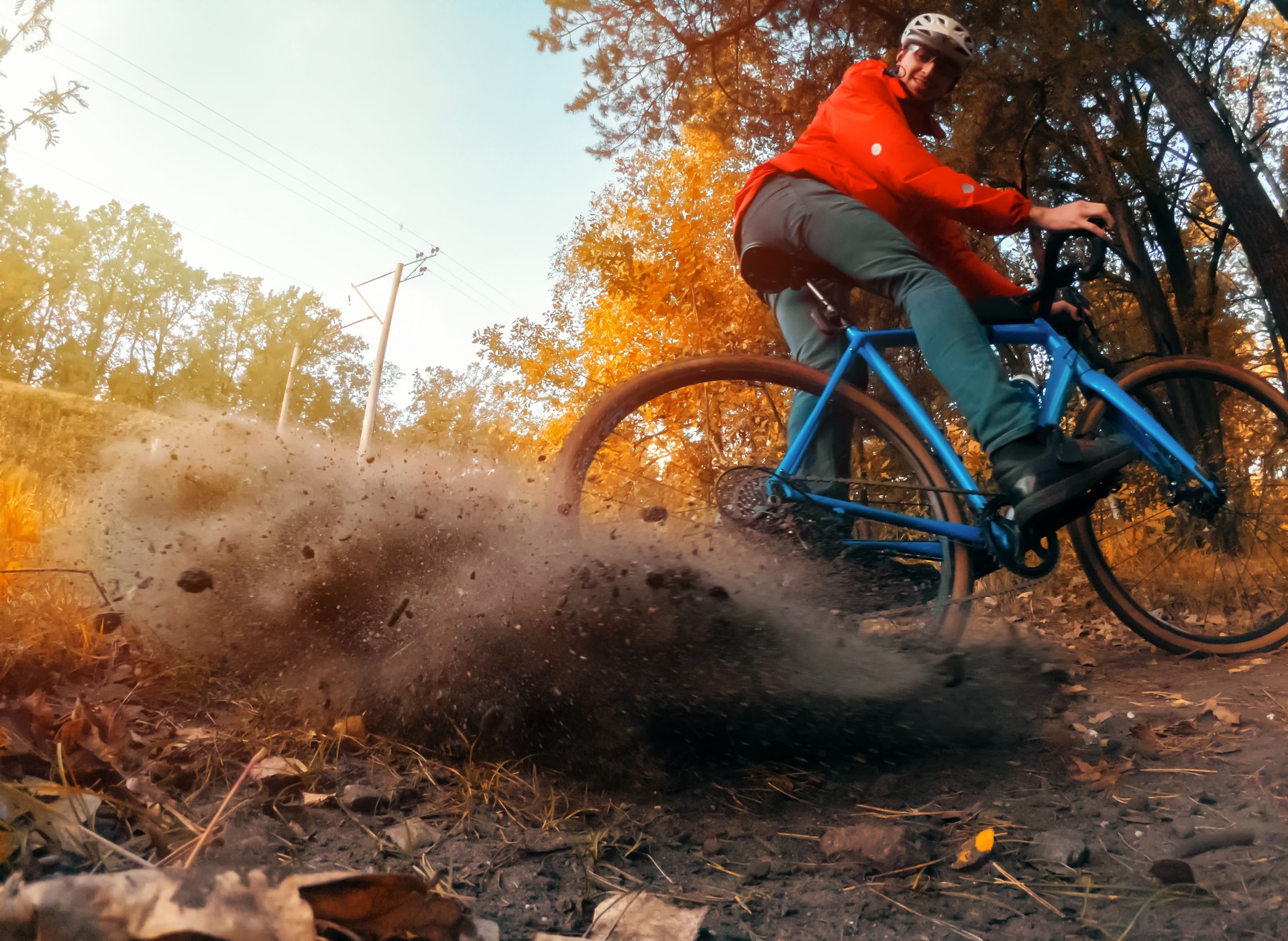 Cyclist rides along the trail, raising up dust from the rear wheel after a skid.