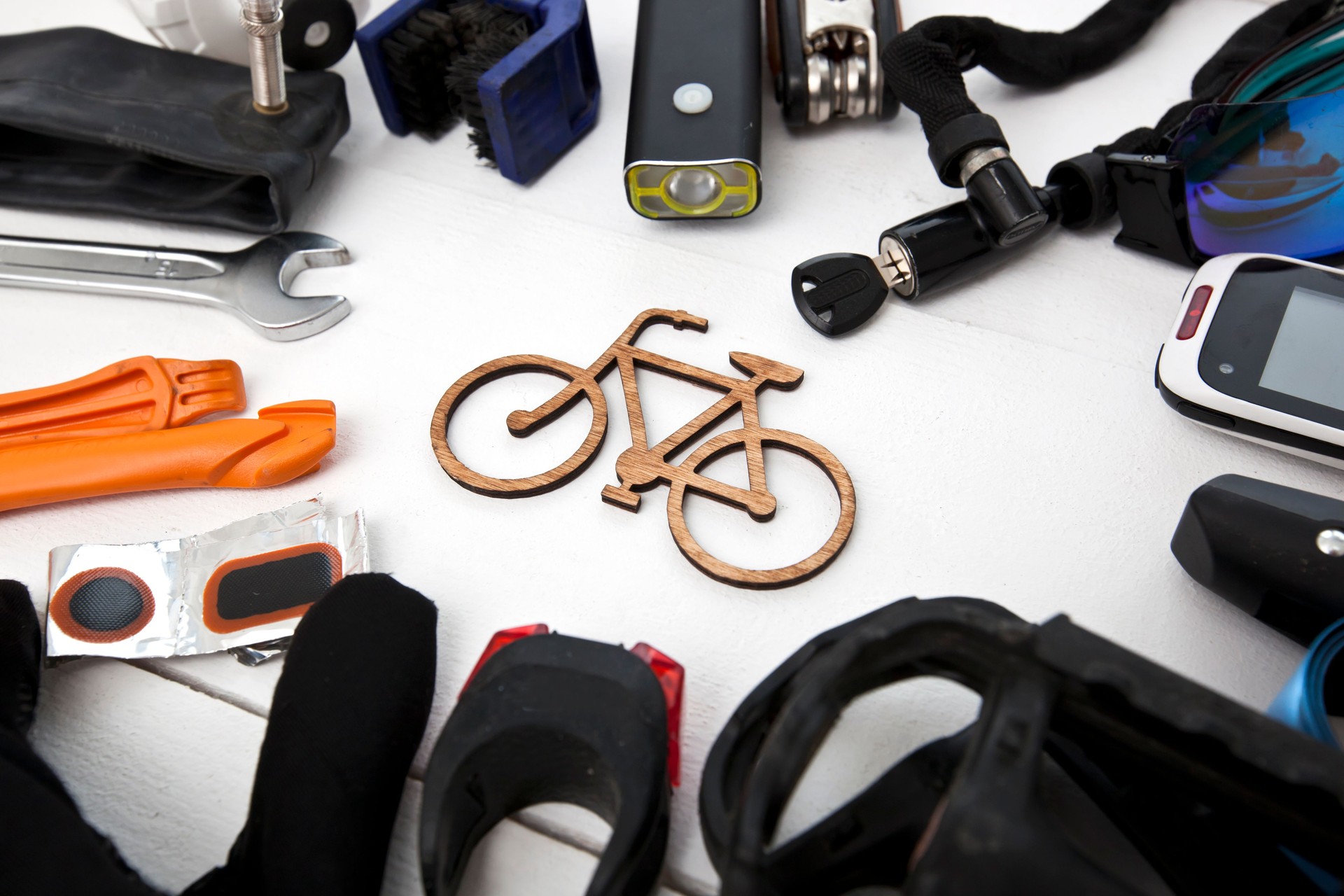 A lot of different bicycle accessories lying on wooden table around a little bicycle icon
